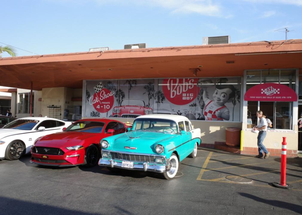 A Bob's Big Boy with three cars parked in front and a person picking up food from a window.