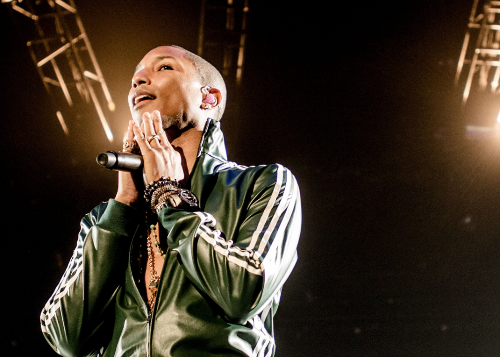 Pharrell Williams holding a microphone onstage.