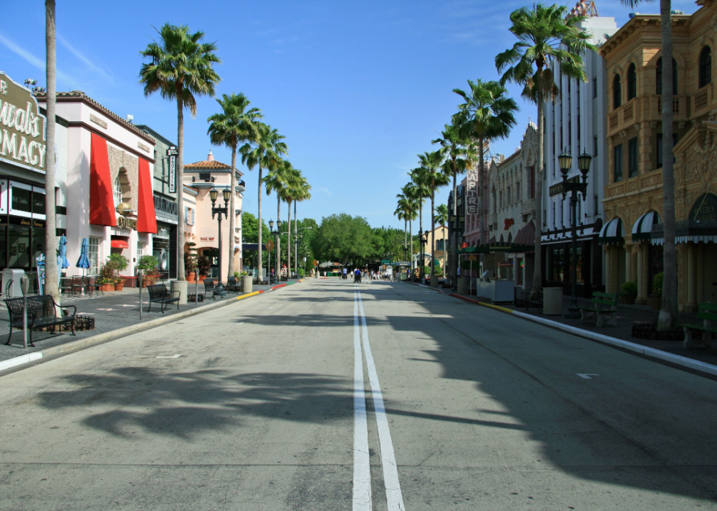 Businesses on a small street lined with palm trees.