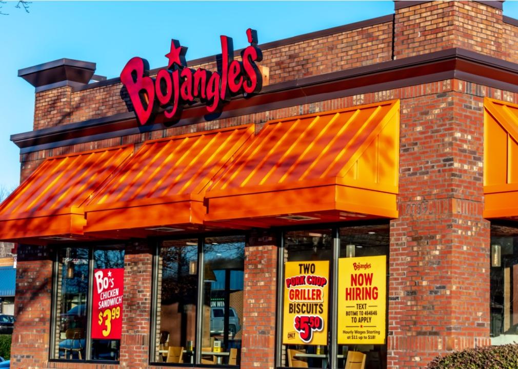 A red brick building with orange slanted overhang and large windows. There is a large sign above the entrance that says Bojangles