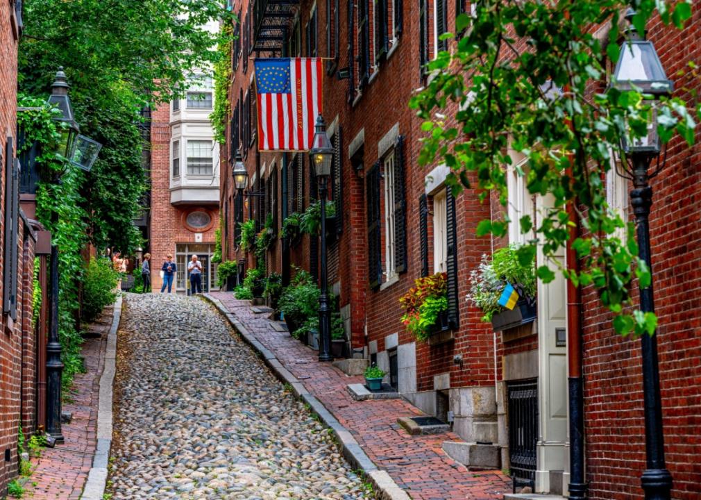 Cobblestone street lined with historic brick buildings. The street is sloping upward