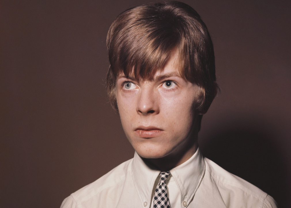 A portrait of a teenage Bowie in a white button up shirt and tie. 