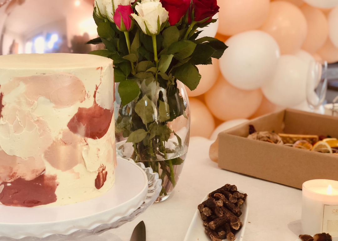 A bridal shower cake, roses and balloons set up on a table.