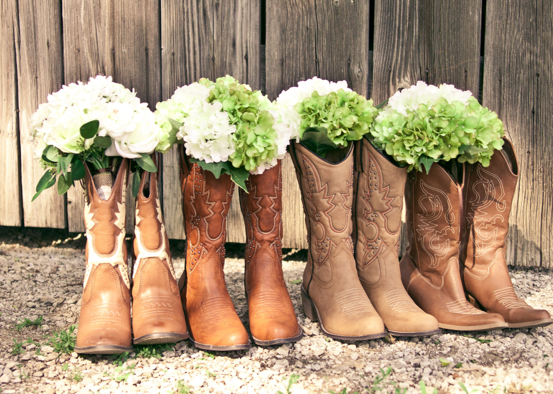 Four pairs of cowboy boots filled with flowers at a country themed bridal shower.