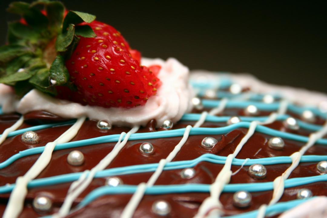 A frosted cake decorated with a strawberry and sprinkles.