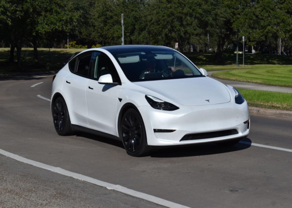 A white Tesla Model 3 driving on the road.