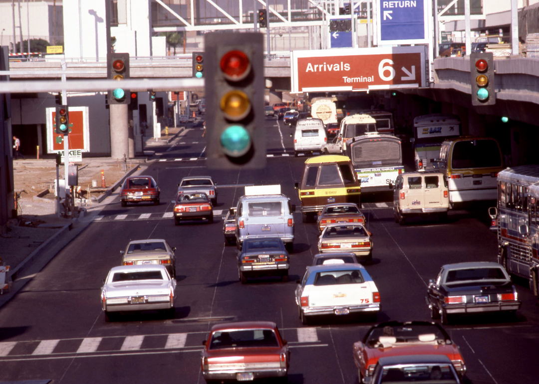Cars and shuttle buses driving through the green light as they go around the Los Angeles International Airport circa August 1983.