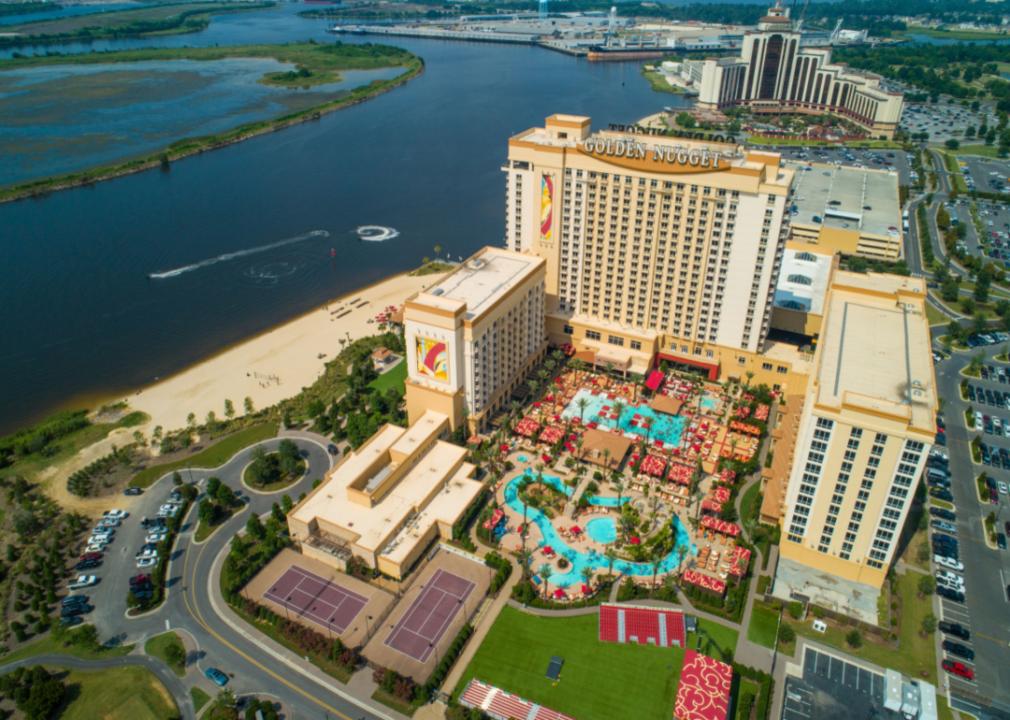 A large casino and pool next to a lake.