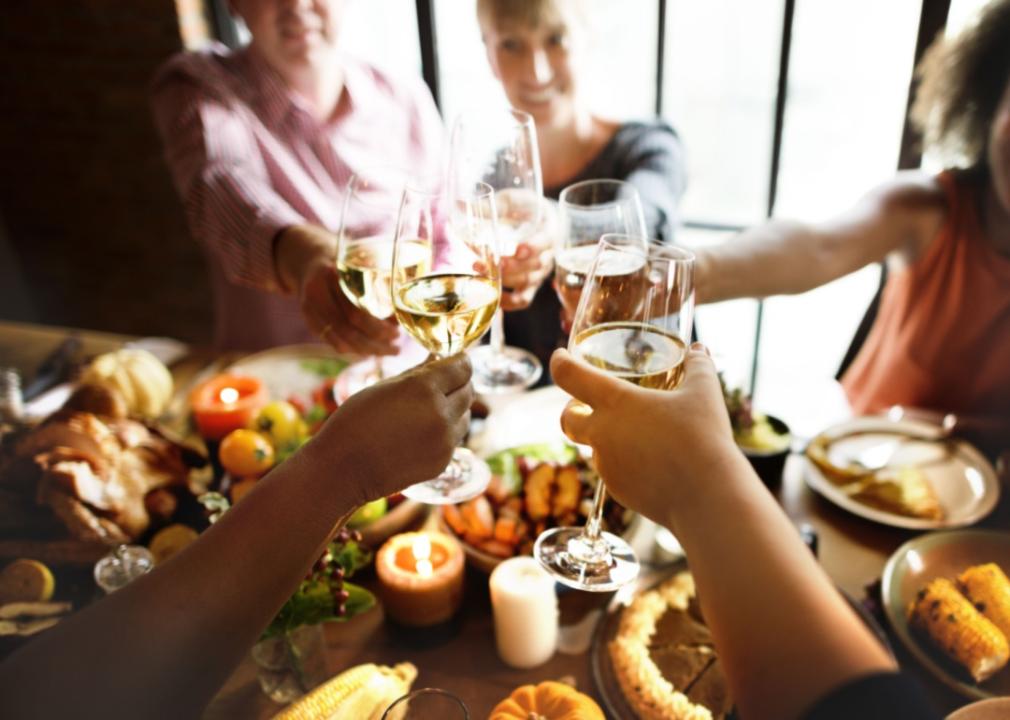 A group of people toasting with their drink glasses over a dinner table.