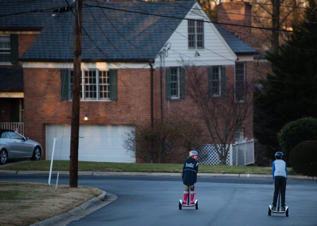 Kids riding scooters in a neighborhood.