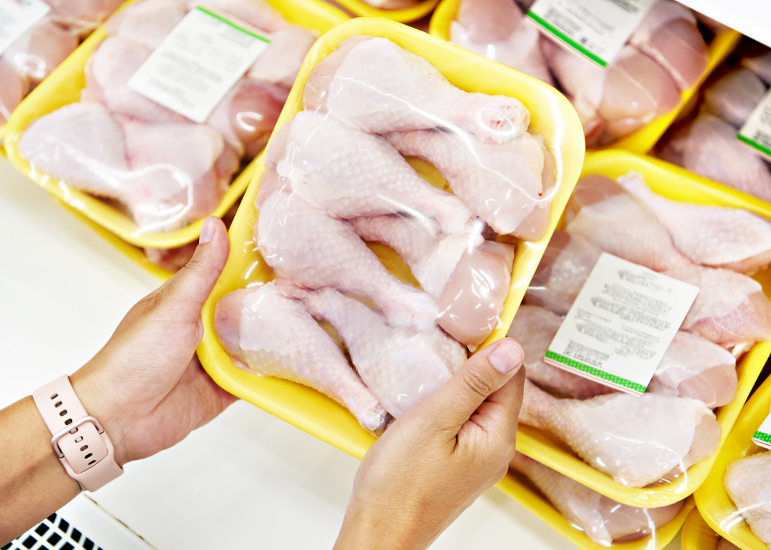 A woman inspects a package of chicken legs