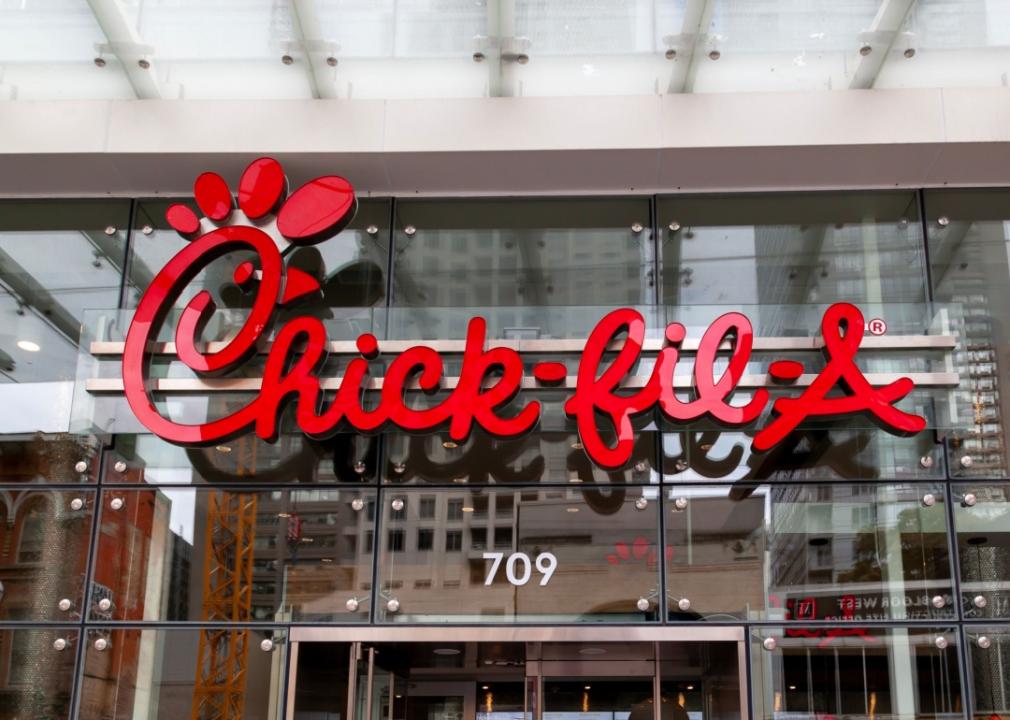 A close up of a red, large Chick-fil-A logo on the facade of modern glass exterior of the building. 