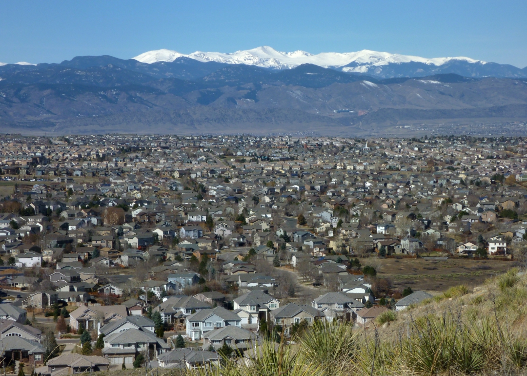 An aerial view of homes with snow-capped mountains in the background.