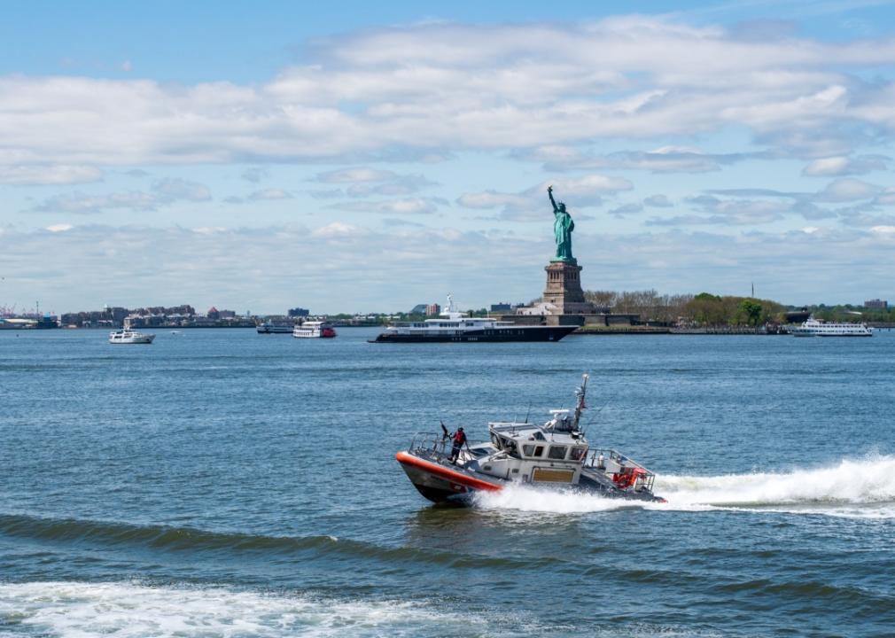 #42. SUNY Maritime College A U.S. Coastguard boat in front of the Statue of Liberty.