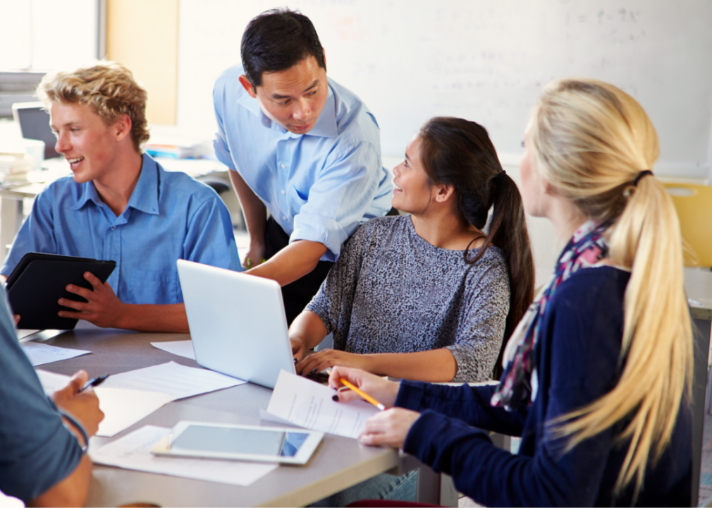 Students with laptops and tablets receive instruction from a professor.