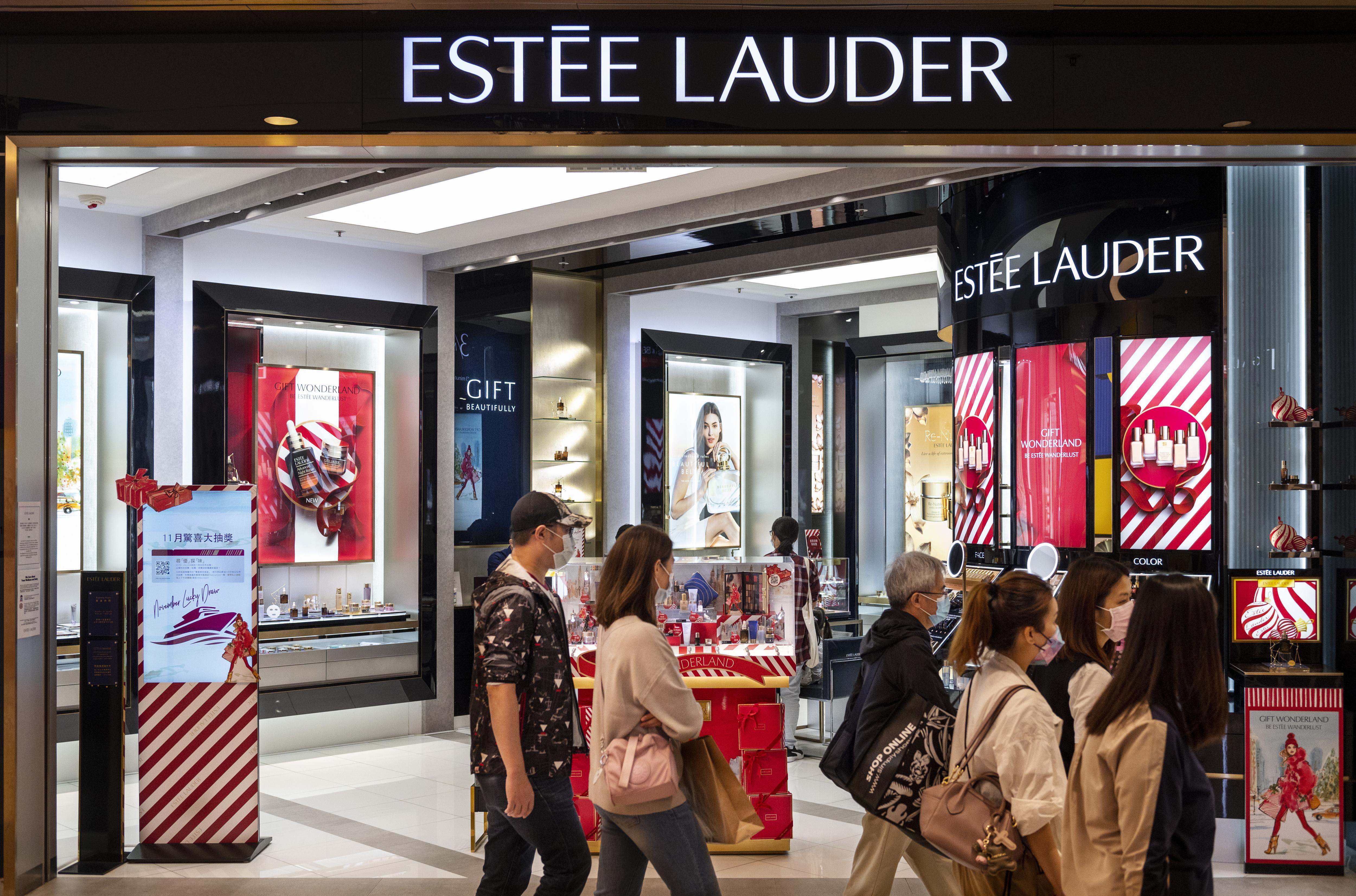 Shoppers walk past an Estée Lauder store in a mall.