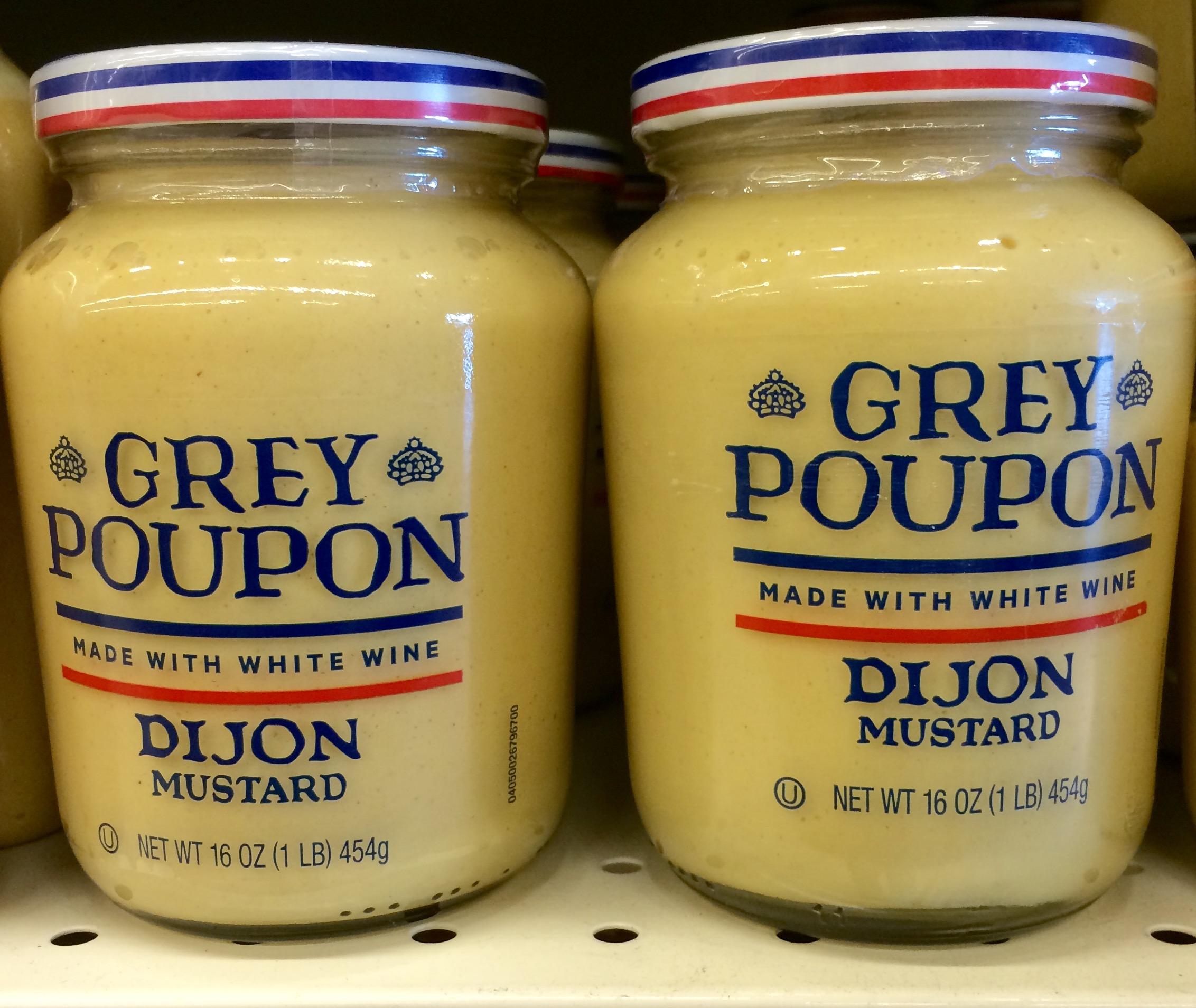 Jars of Grey Poupon on a grocery shelf.