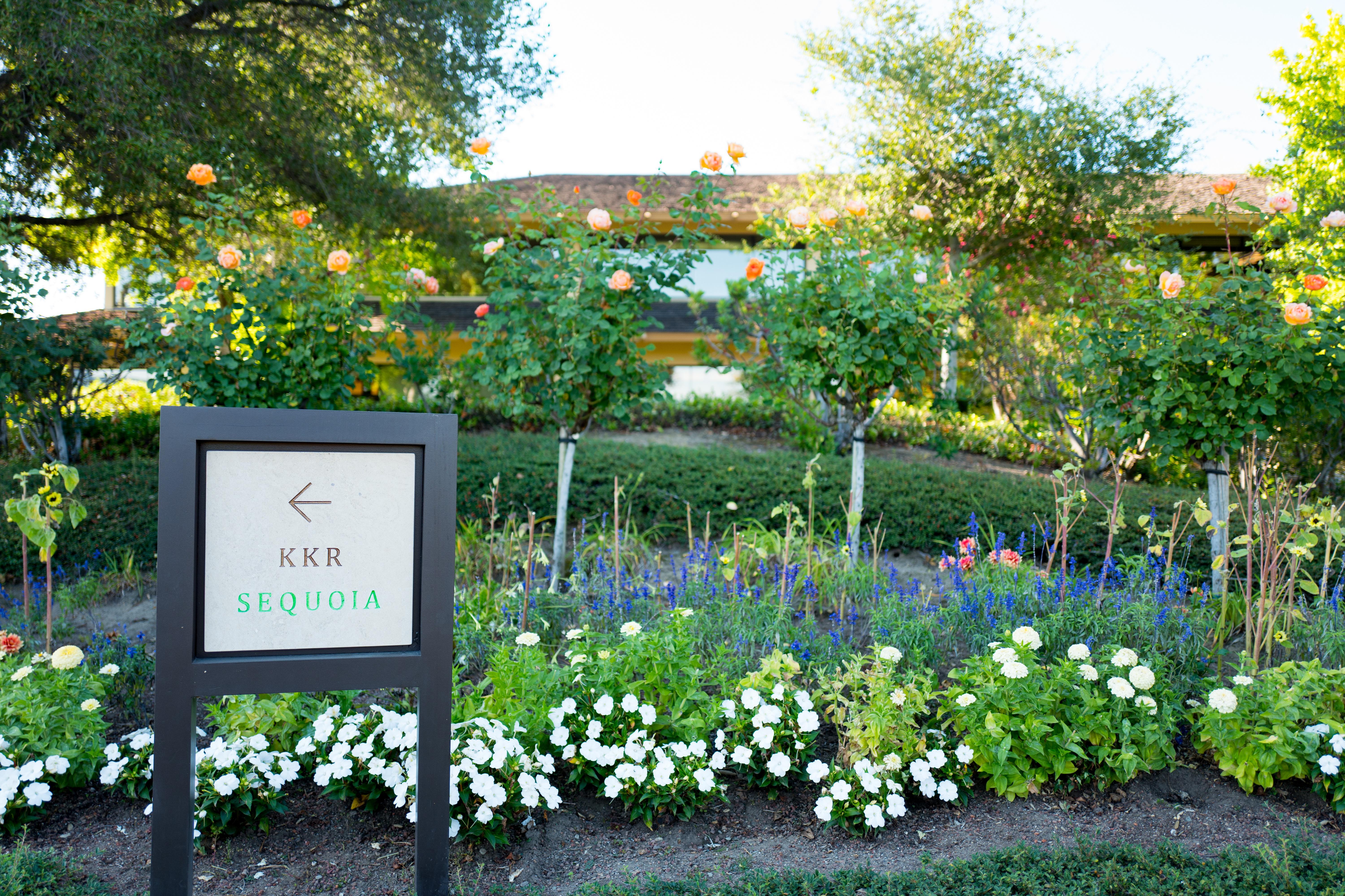 A KKR sign in front of a flower bed.