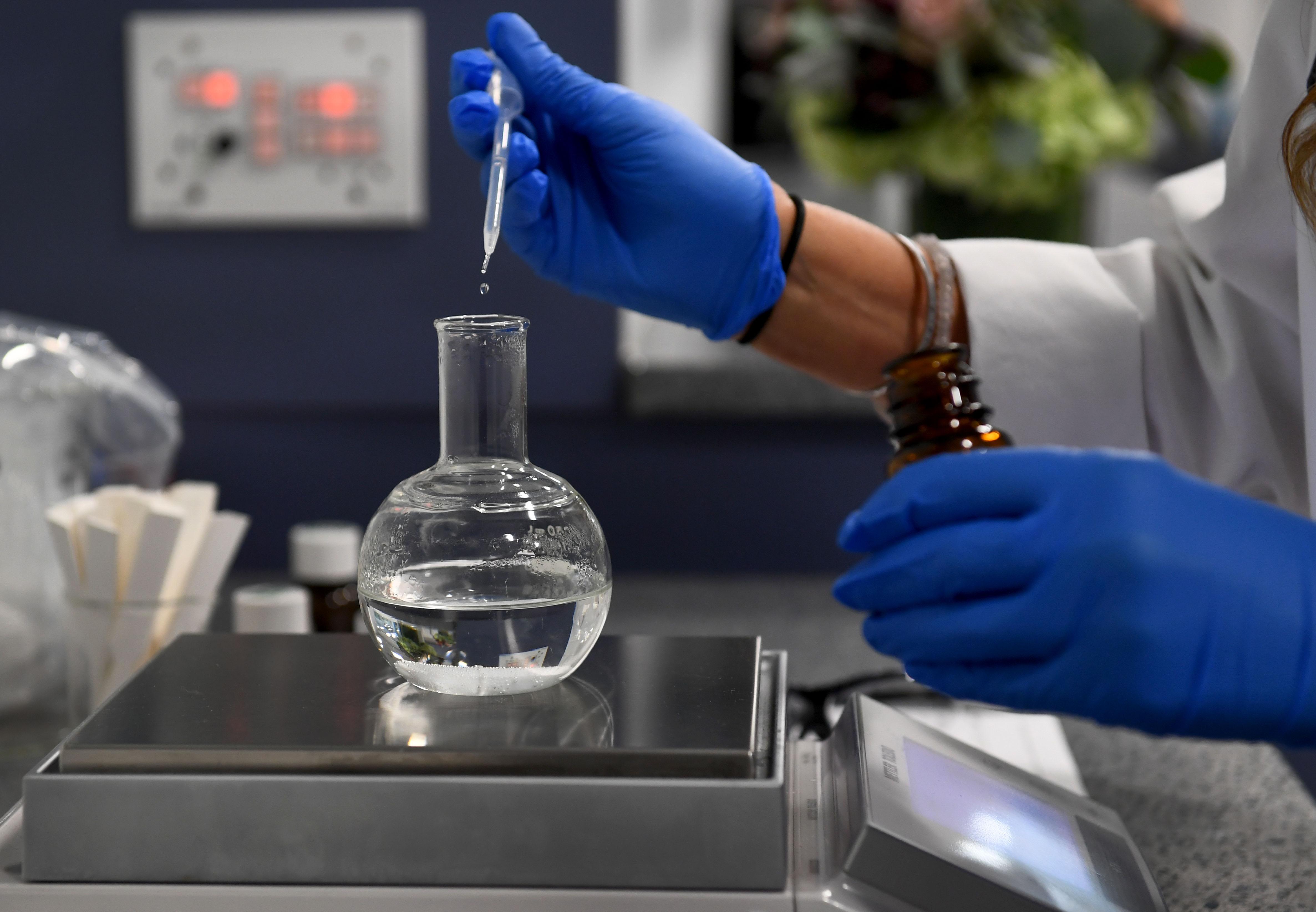 A flavorist drops liquid into a beaker.