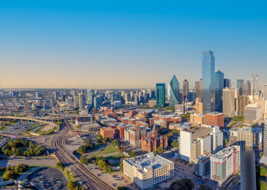 City skyline is dominated by tall skyscrapers in the center, with a mix of shorter buildings and structures spreading out towards the edges of the image. A network of highways and roads crisscrossing the city.