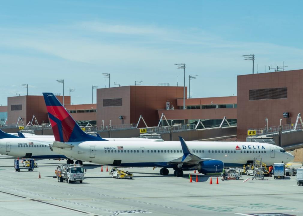 Multiple commercial Delta airplanes parked at an airport gate on a clear sunny day. 