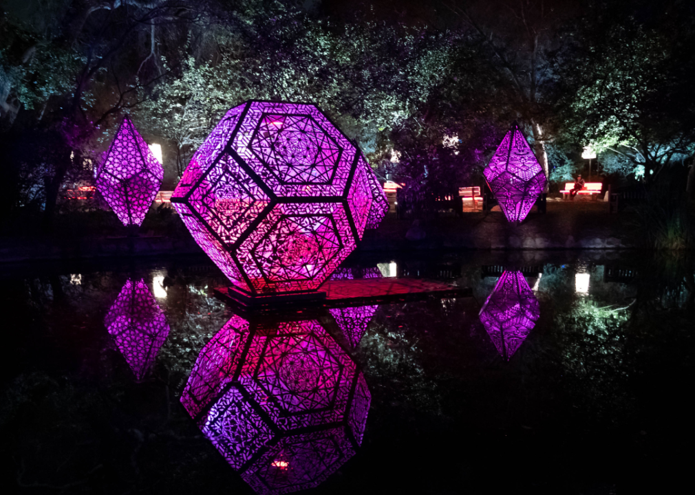 Large illuminated geometric sculptures adorn a water feature.