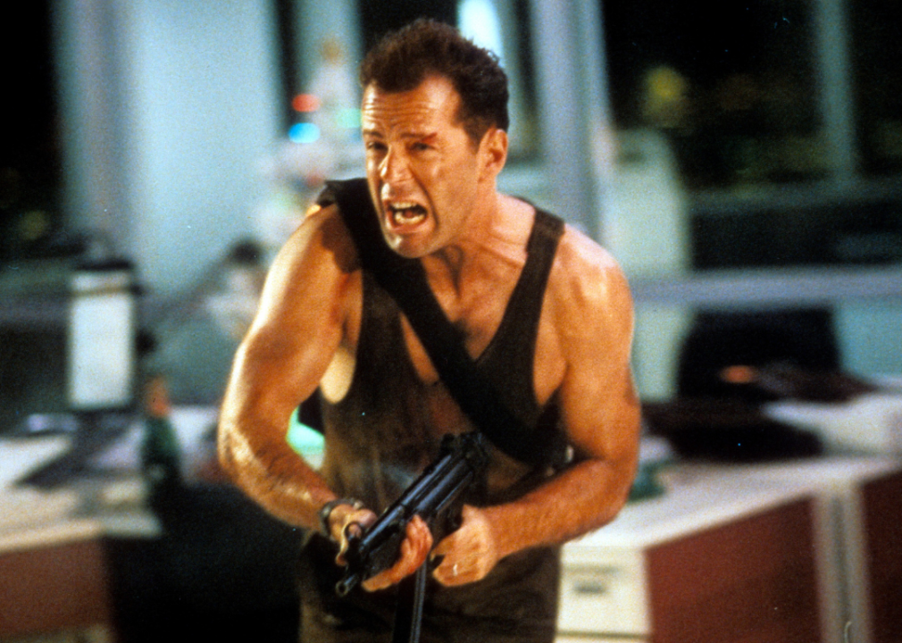 Bruce Willis running with automatic weapon in a scene from the film 'Die Hard'.