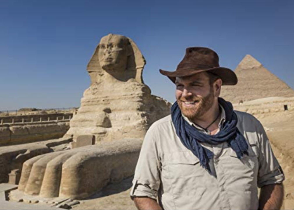 Host Josh Gates poses in front of the Sphinx