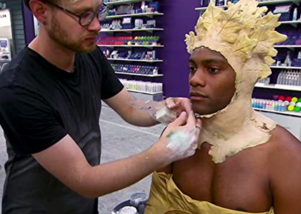 A contestant applies prosthetic makeup to a model