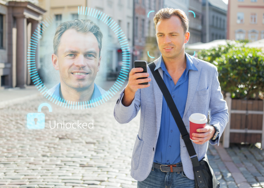 A man holding a phone in his hand with a close up of his face next to him. 