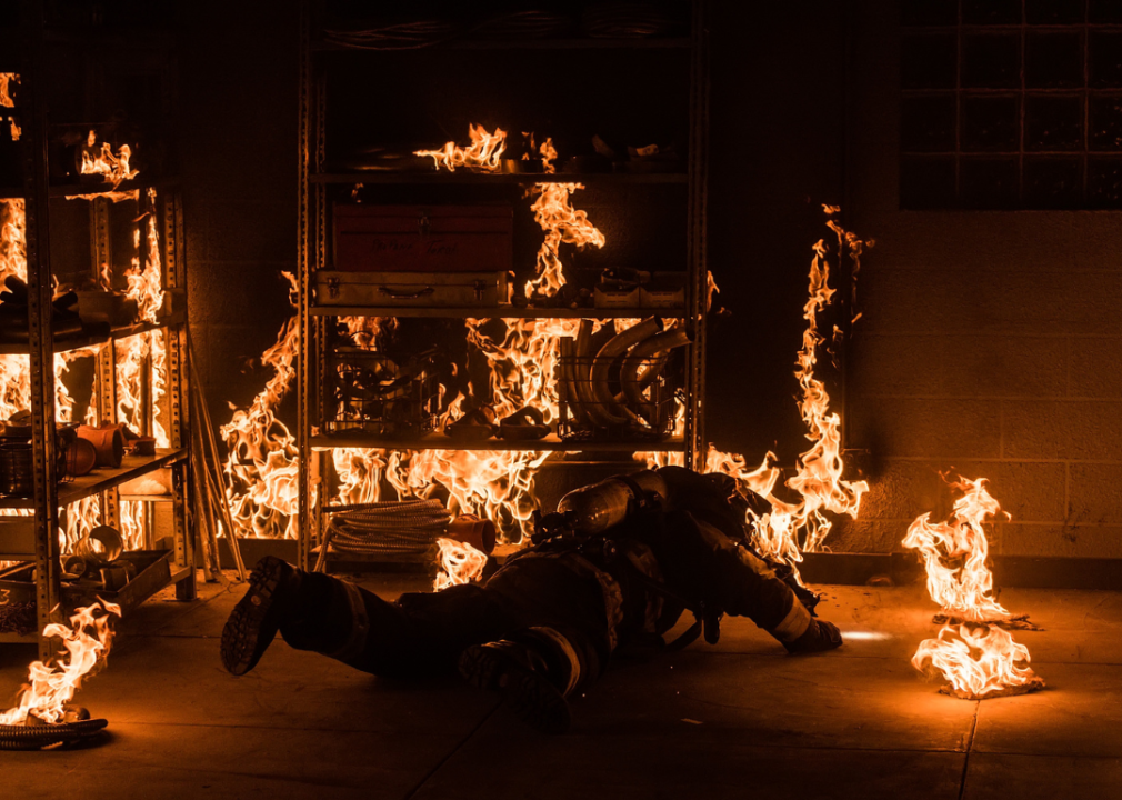 A fireman on the floor in a burning room.