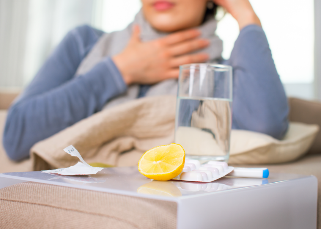 A woman wearing a scarf sits behind a water glass and a lemon wedge