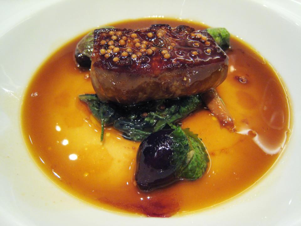 A dish of foie gras drenched in sauce.