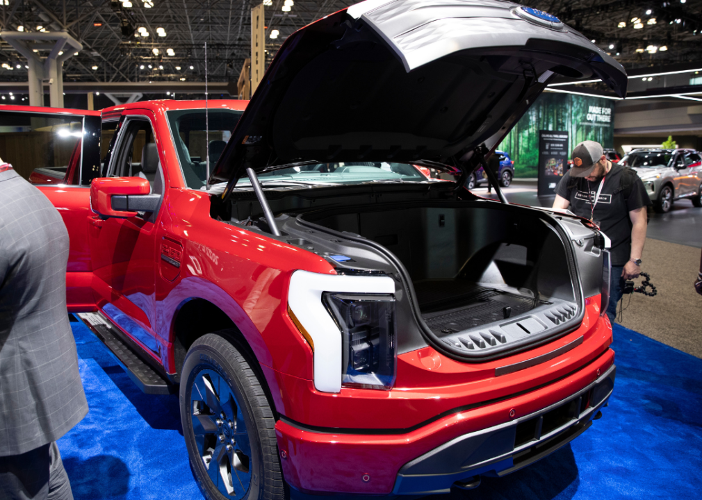 A red Ford truck EV in a showroom with the hood open.