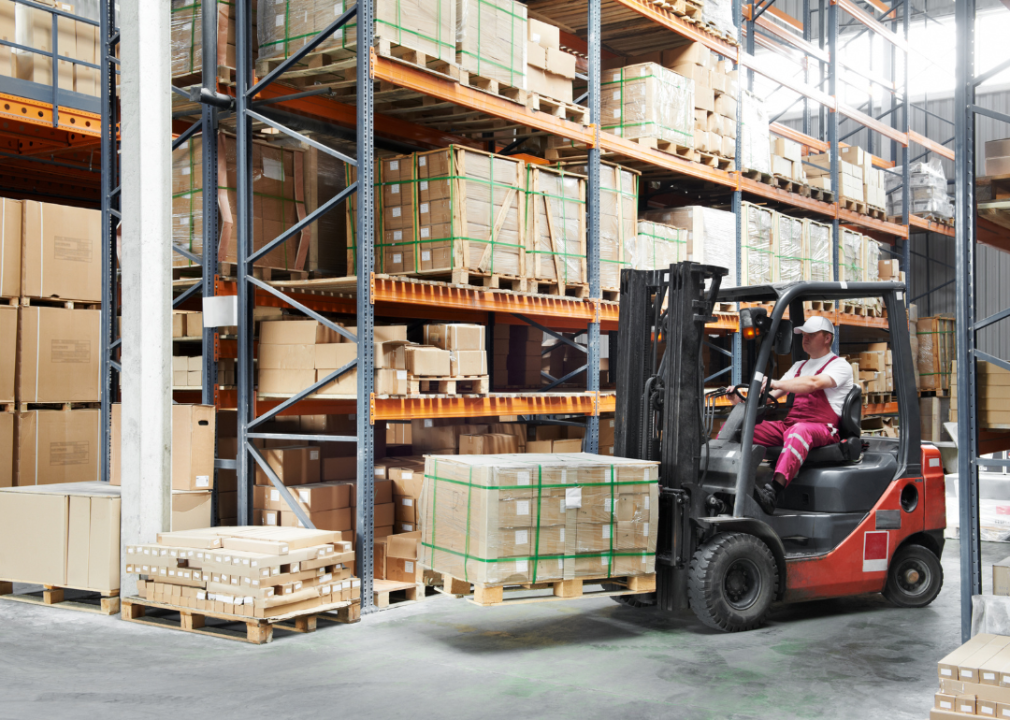 A man in the forklift with a load in a large storage room.