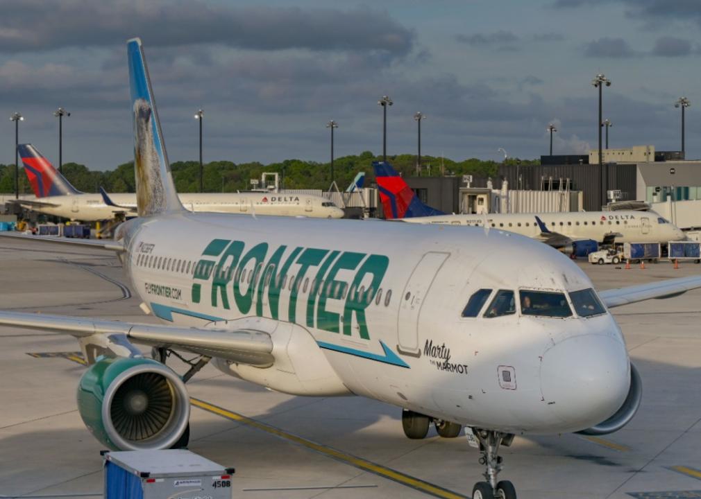 Frontier Airlines airplane on the tarmac at an airport. Airline green logo Frontier displyed on the plane. 