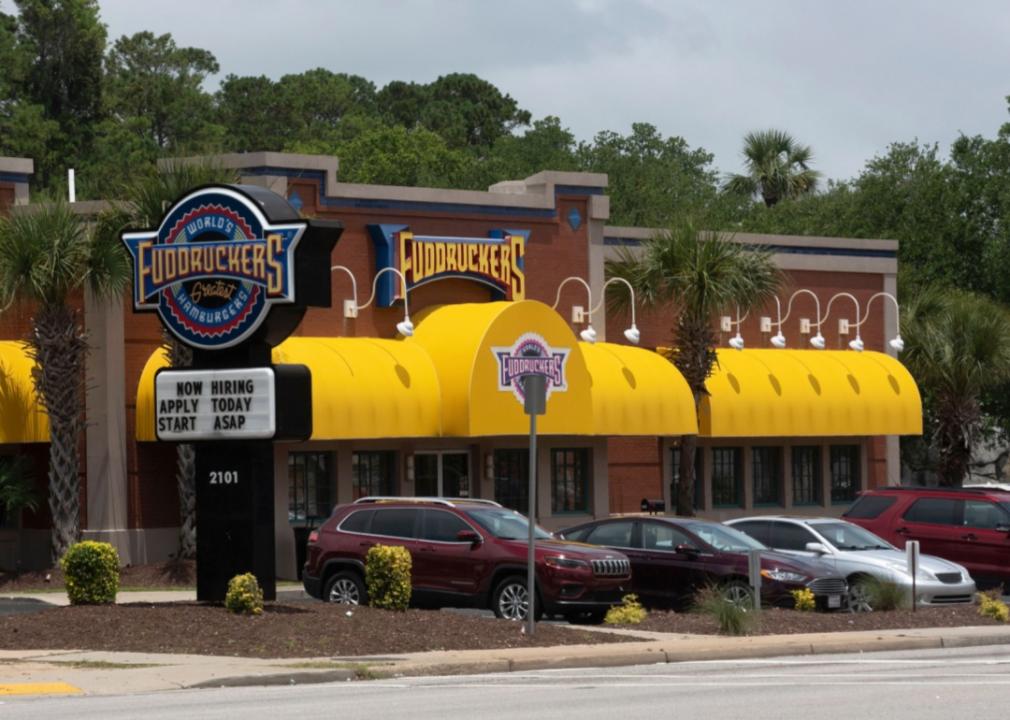 The exterior of the Fuddruckers restaurant, which has a red facade with bright yellow awnings.