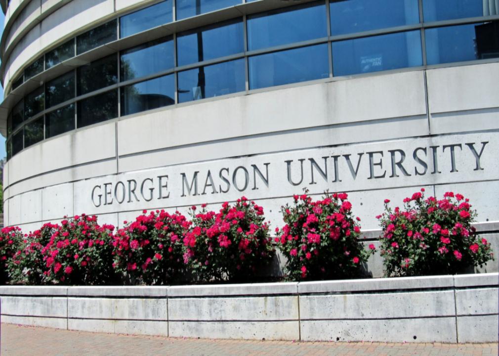 A close up of large, concrete building with many windows and a sign that says George Mason University. 