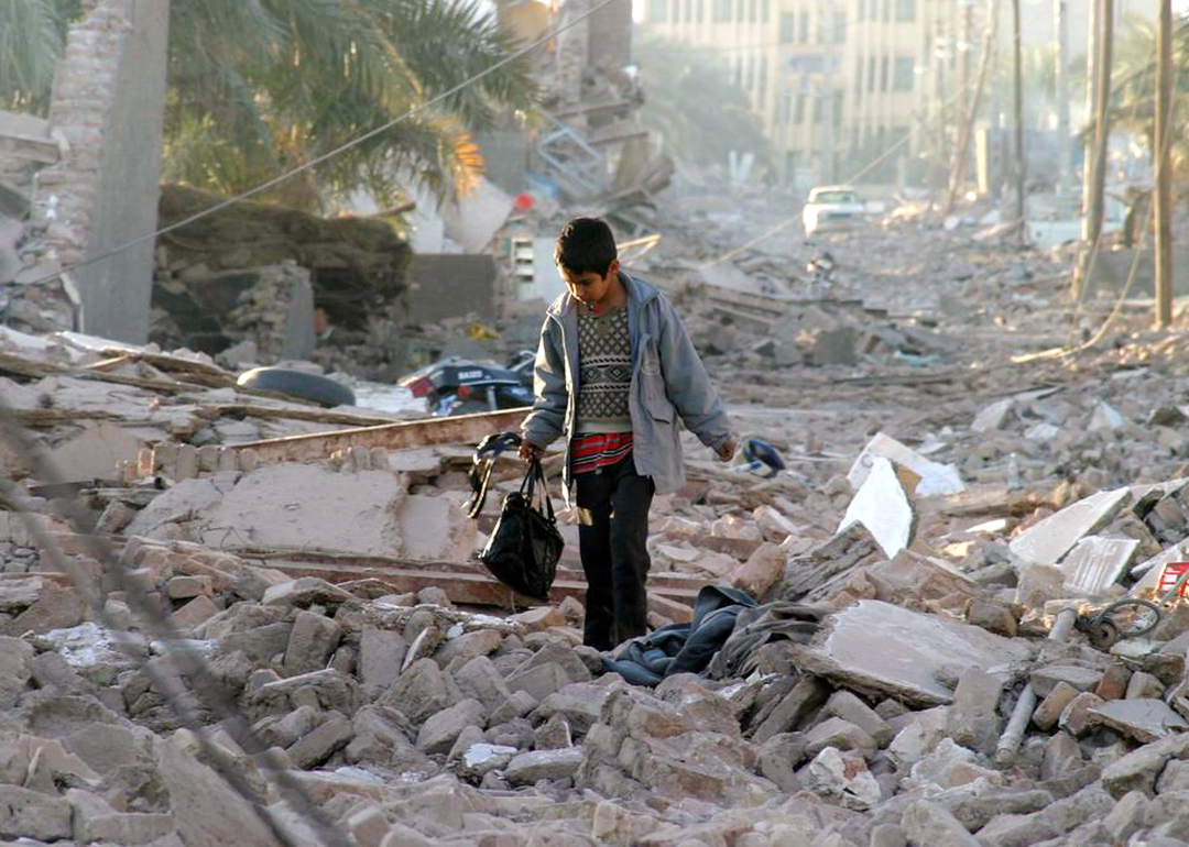 A boy carrying a bag walks through the street of his destroyed neighborhood in Bam, Iran
