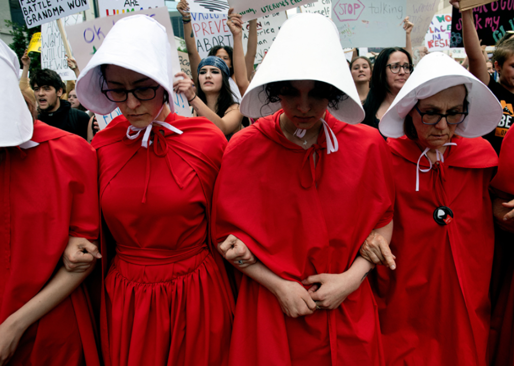 Demonstrators in an outfits from The Handmaid's Tale participate in a march in Denver.