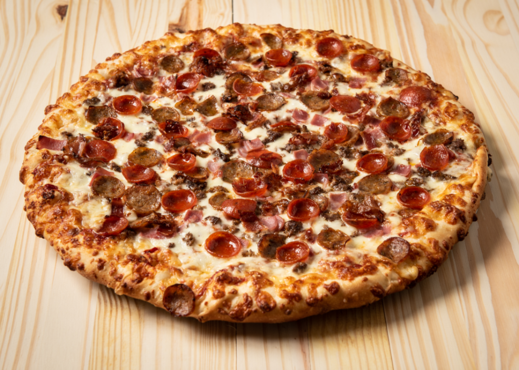 Sausage and pepperoni pizza on wooden surface.