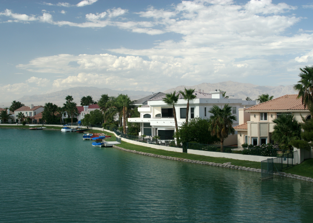 Large homes on the water with mountains in the background.
