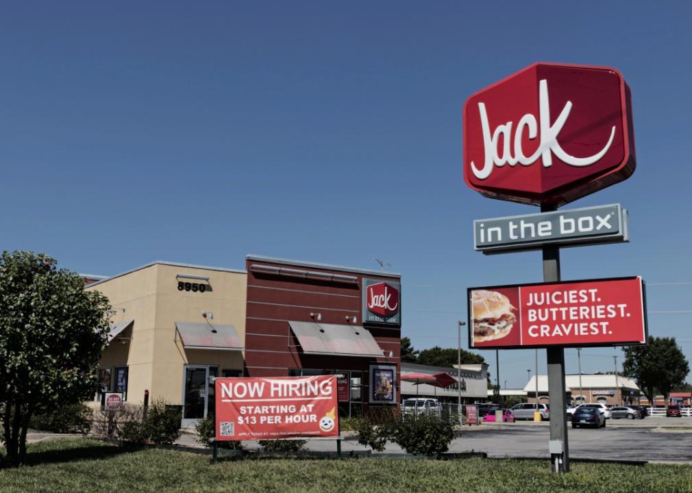 Jack in the Box restaurant with a large sign towering next to the building and a smaller sign advertising job openings in front of the building.