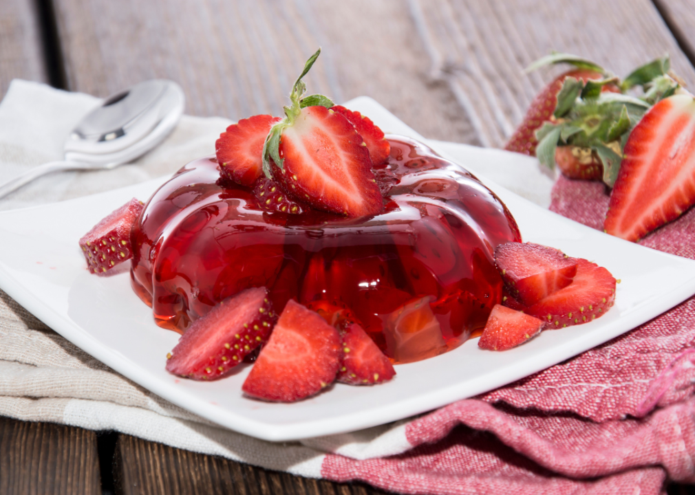 A plate of red jelly with sliced strawberries inside and on top.