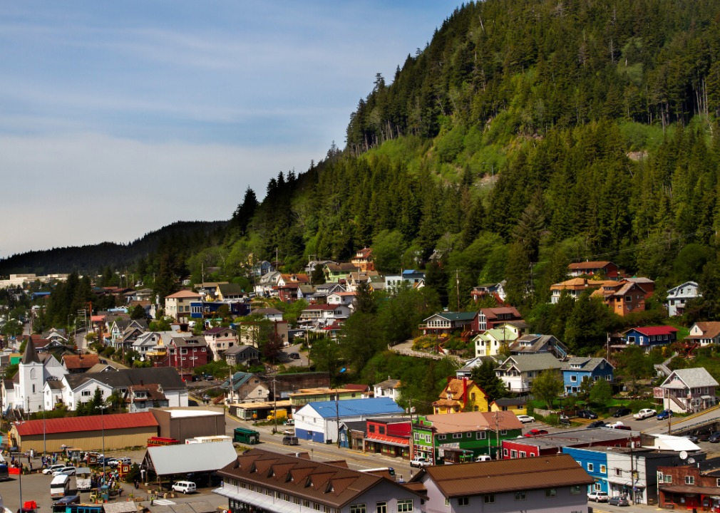 A small town made up of mostly single-family homes, with a few businesses and a church in the center, nestled in a valley surrounded by mountains and trees.