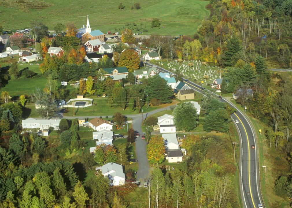 An aerial view of the town surrounded by grassy fields and mature trees. 
