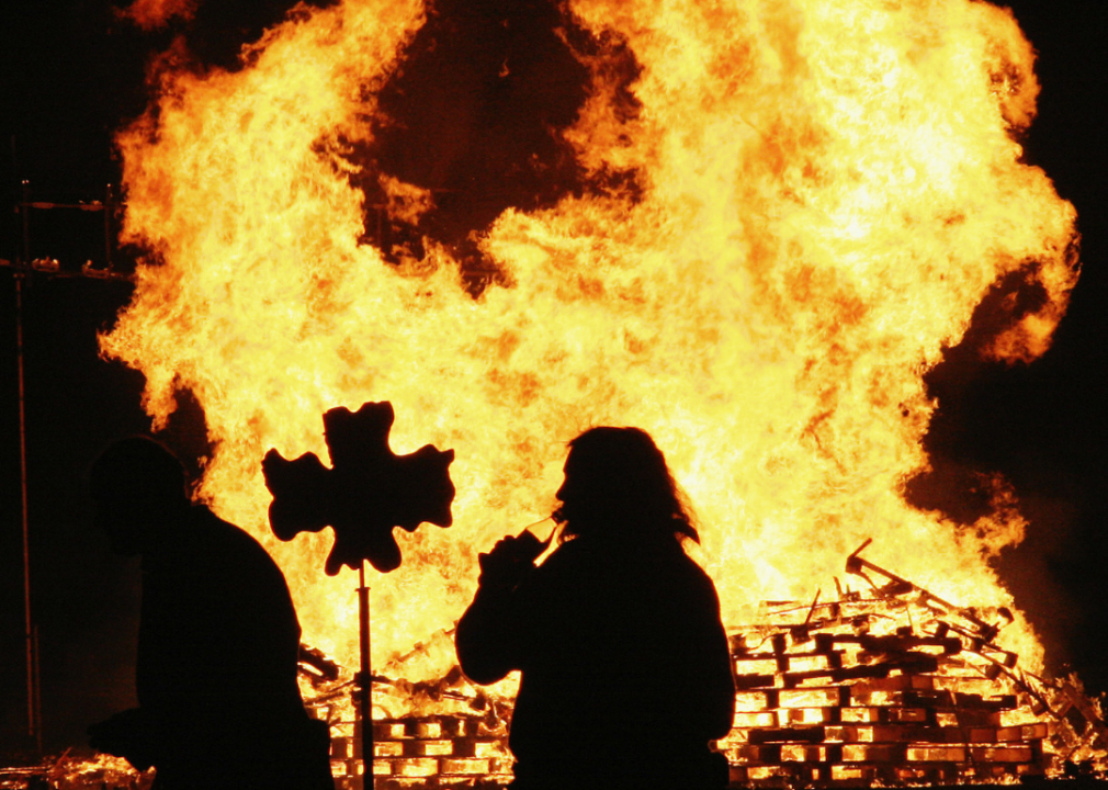 A reveler is standing by the bonfire during the Bonfire Night celebrations which is related to the ancient festival of Samhain.