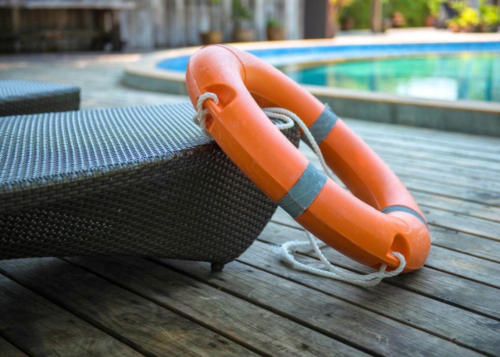 A life ring on a lounge chair next to a pool.