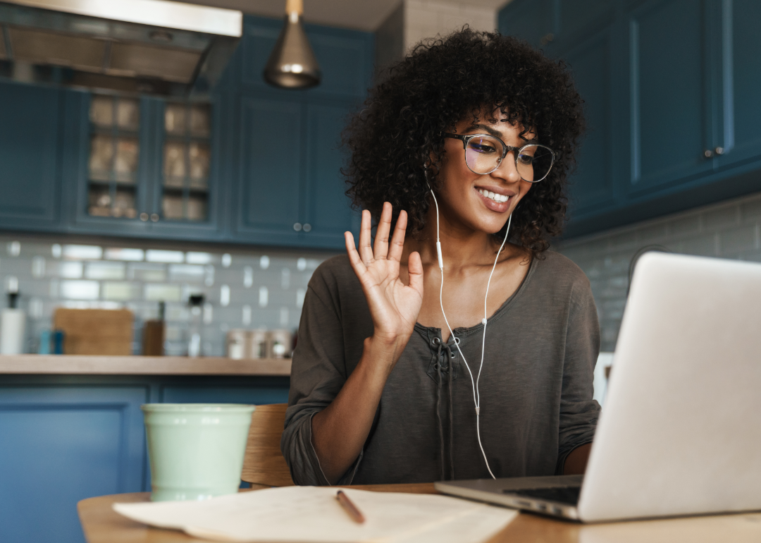 A woman waves goodbye to her laptop screen