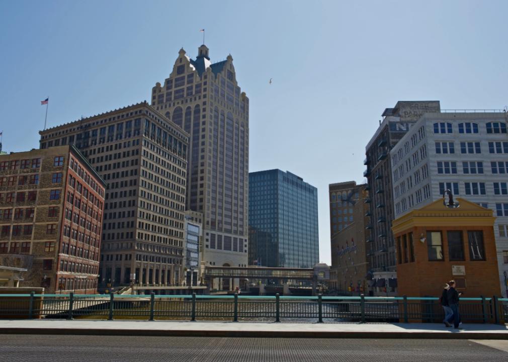 A city with a river flowing through it. A mix of architectural styles, from modern high-rises to older buildings with decorative features.